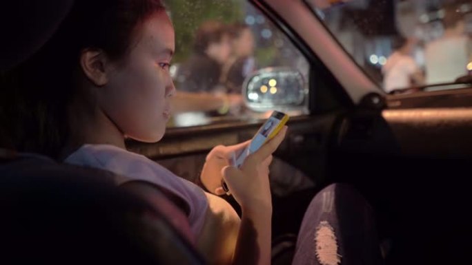 十几岁的女孩在汽车中使用智能手机，背景是交通车
