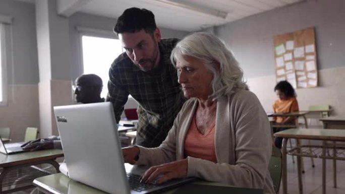 男老师在上课时使用笔记本电脑时检查一名高级妇女的工作