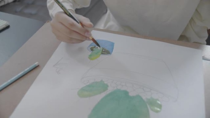 POV手持特写拍摄亚洲少女在客厅手绘和绘画她的艺术。她使用笔记本电脑与朋友进行视频通话，同时使用水彩