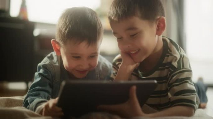 两个亚洲男性孩子的肖像在周末在他们的房间里使用数字平板电脑。两个可爱的兄弟一起看动画片，专注于屏幕，