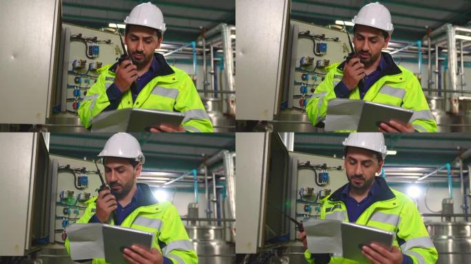 一名男性工程师使用无线电来解决工厂内控制柜的问题