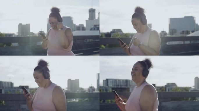 开朗的大码女性锻炼并使用电话跟踪她在城市中的失重和进步。戴着耳机的曲线女性享受音乐播放列表，同时通过