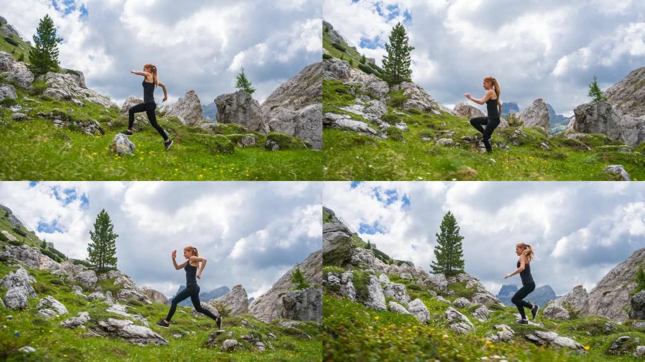 女运动员在草地上绿草如茵的岩石小径上奔跑，被群山环绕