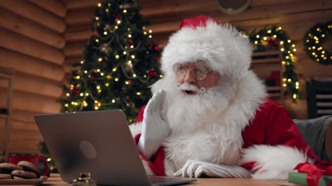 圣诞老人正在用他的笔记本电脑与各种各样的情感愉快地视频聊天