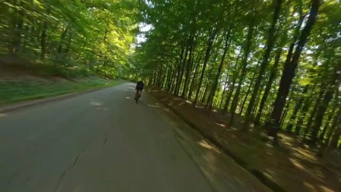 晴天，空中休闲骑自行车的人快速驶过森林