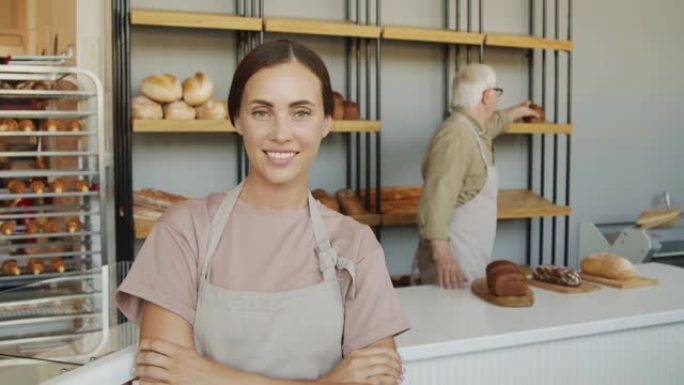 年轻的女面包店员工摆姿势