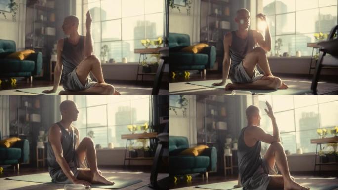 年轻英俊的男性早上在他阳光明媚的阁楼公寓锻炼、伸展和练习瑜伽。健康的生活方式、健身、幸福和正念概念。