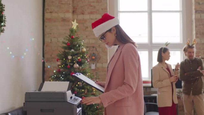 穿着圣诞老人帽子的女商人在办公室使用复印机