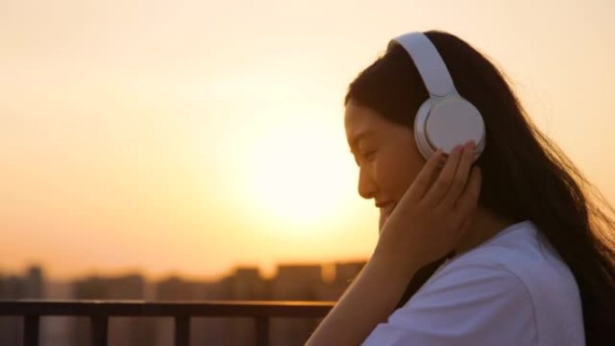 戴着耳机的女孩在日落时听音乐