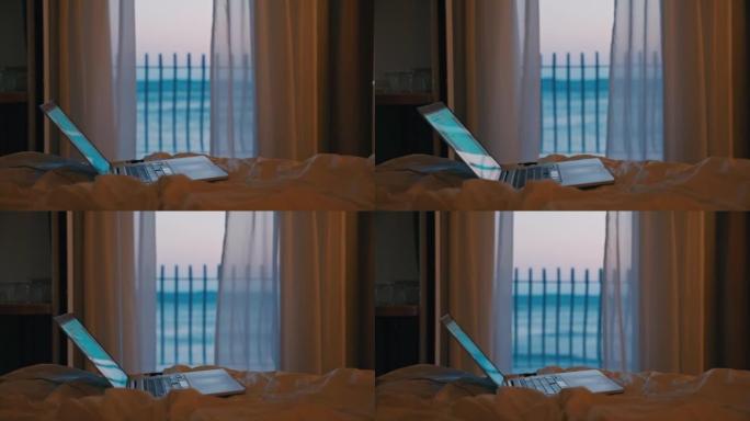 笔记本电脑站在酒店房间的床上，晚上可以看到大海，多莉运动