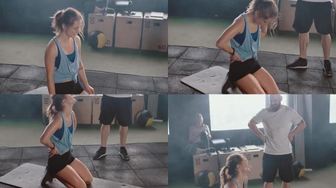 年轻快乐的运动高加索女人在与男教练一起锻炼后非常疲倦，在健身房脚垫上呼吸沉重。