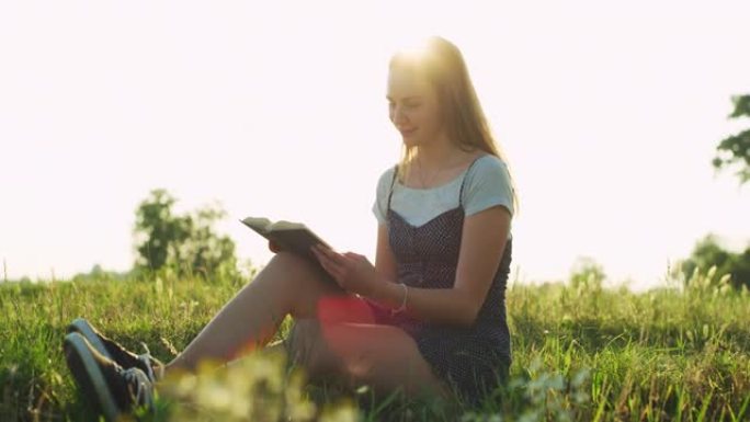 一个年轻的金发幸福的女人的真实镜头正在田野里看书