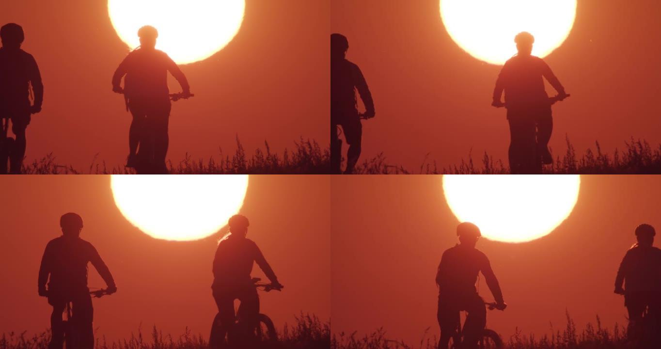 日落时两名骑自行车的人骑山地自行车的剪影