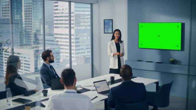 办公室会议室会议演讲: 亚洲女商人演讲，使用绿屏色键墙电视。成功地向不同的投资者群体展示产品。商人鼓