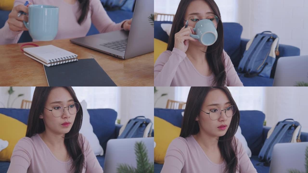 特写镜头迷人的年轻亚洲女性在家里做生意时在笔记本电脑上工作或打字，喝咖啡。女性在家工作或远程工作时在