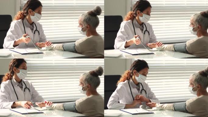 年轻女医生检查老年女性患者的血压。