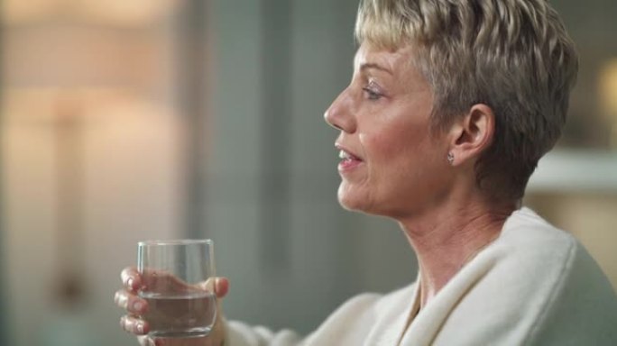 4k视频片段，一名高级妇女坐在家里喝一杯水