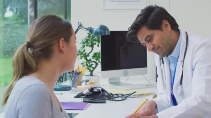 男性医生或全科医生穿着白大褂与十几岁的女孩预约在剪贴板上做笔记-慢动作拍摄
