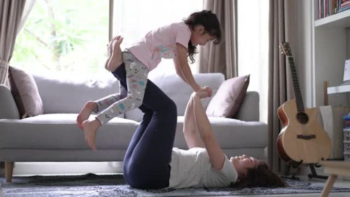 健康的妈妈和女儿在家里的客厅快乐和有趣的玩耍平衡