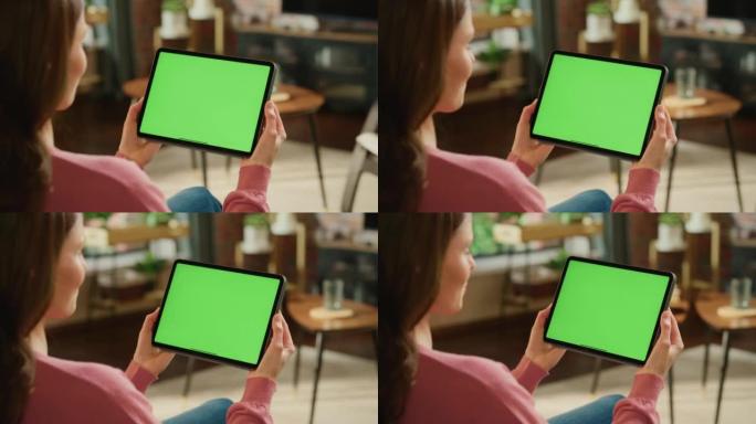 女性手持平板电脑，绿屏模拟显示。女人在家放松，在移动设备上观看视频和阅读社交媒体帖子。特写镜头。