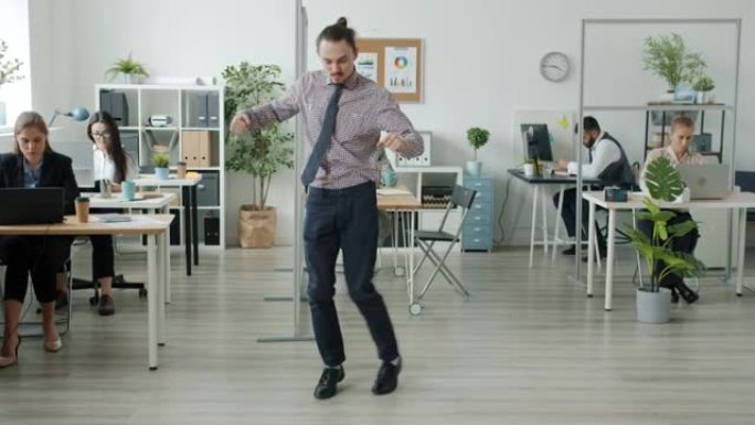 有趣的人在办公室跳舞的肖像，而商人在背景中工作