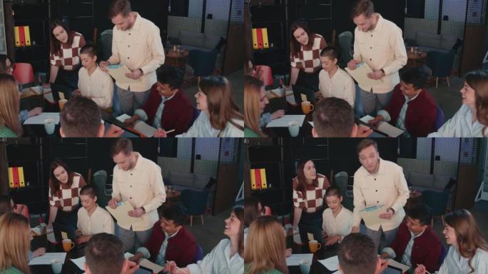 高角度镜头，年轻商人在办公室工作台会议慢动作时与团队讨论营销数据表。