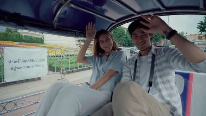 年轻英俊的男人和他的女朋友骑着传统的嘟嘟车夫妇在蜜月期间旅行泰国