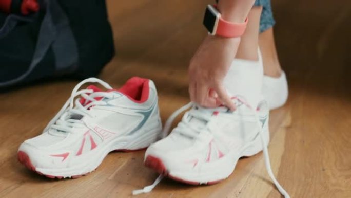 4k视频片段，一名妇女在家中系鞋带以准备锻炼