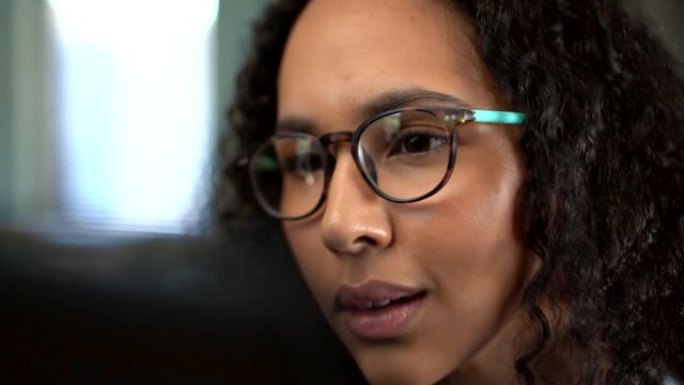 年轻的混血女商人在笔记本电脑上工作时戴着眼镜的特写镜头。坐在办公室的西班牙裔女企业家专注于阅读电子邮