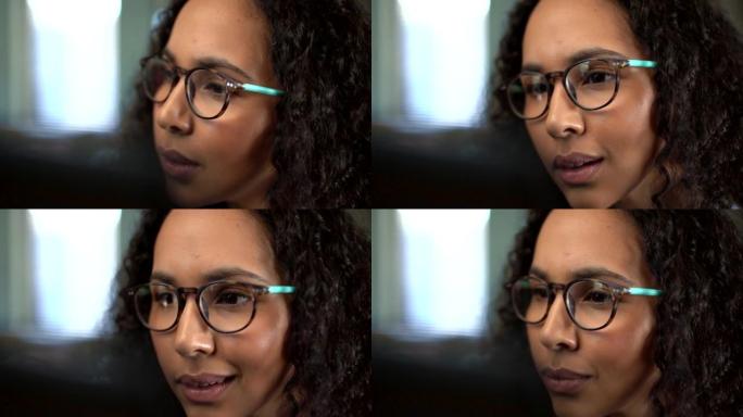 年轻的混血女商人在笔记本电脑上工作时戴着眼镜的特写镜头。坐在办公室的西班牙裔女企业家专注于阅读电子邮