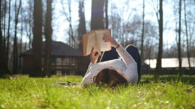 女人躺在公园的草地上读书