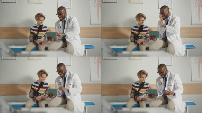友好的非裔美国家庭医生与一个带手臂支架的小男孩交谈，并在平板电脑上显示测试结果。快乐的医疗保健医生在