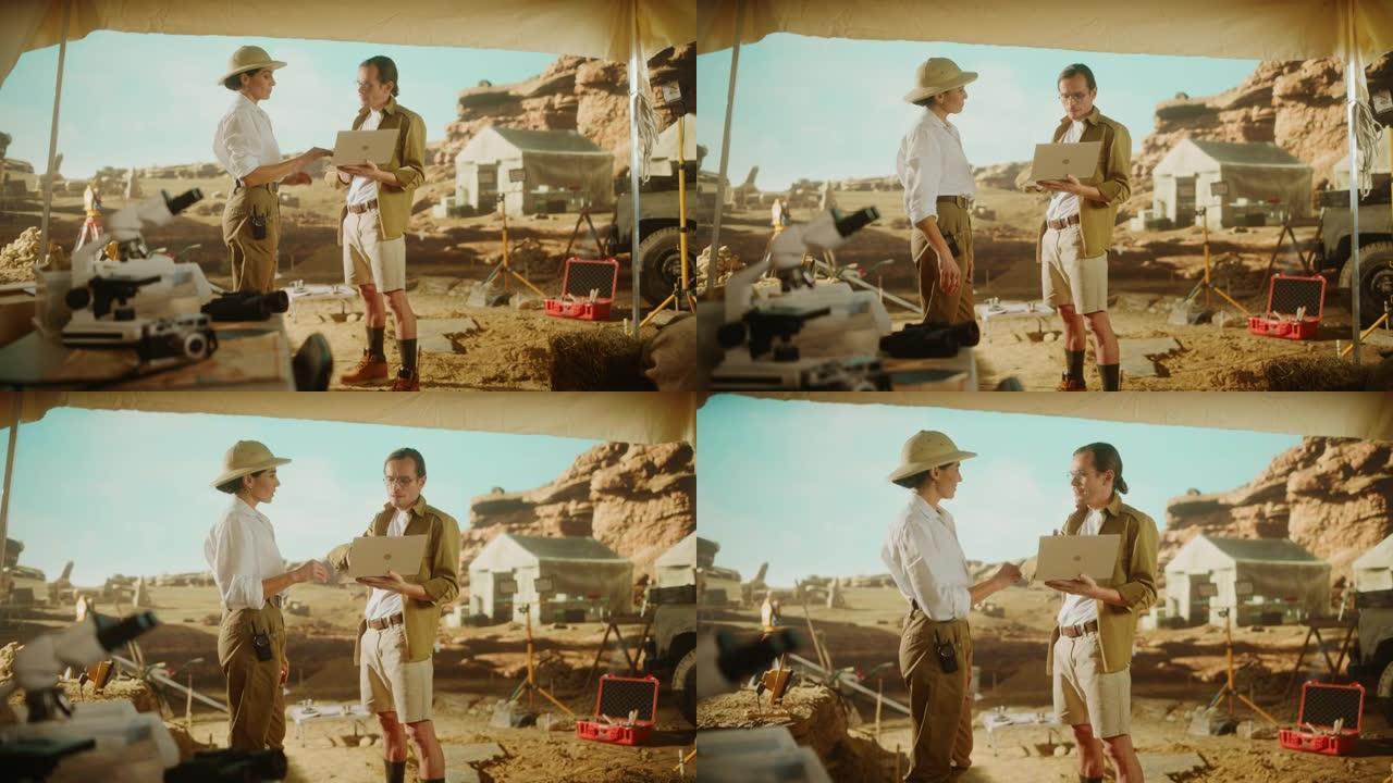 考古挖掘现场: 两位伟大的考古学家站在发掘现场的帐篷工作中，使用笔记本电脑检查新发现的古代文明建筑遗