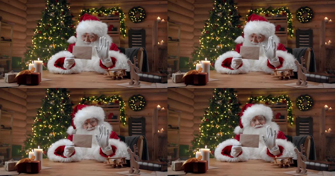 装饰精美的室内圣诞老人拿着一个干净的信封，微笑着对着镜头挥手，