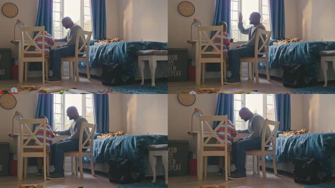 4k视频片段，一个英俊的成熟男人在他的卧室里帮助他做作业时向儿子击掌