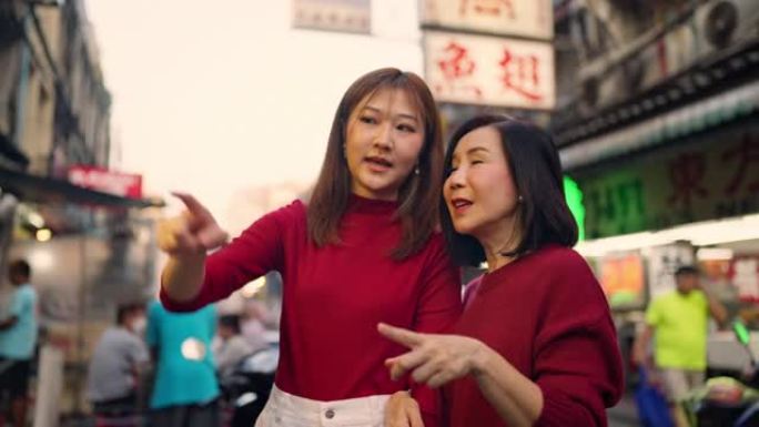 亚洲母女在农历新年在唐人街旅行和吃街头美食。