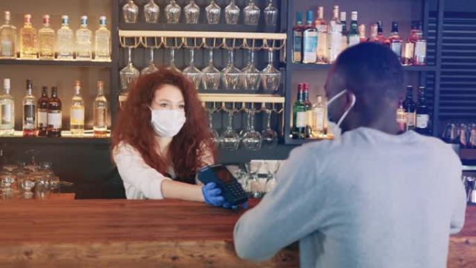 戴着口罩的咖啡馆女服务员正在接受NFC付款