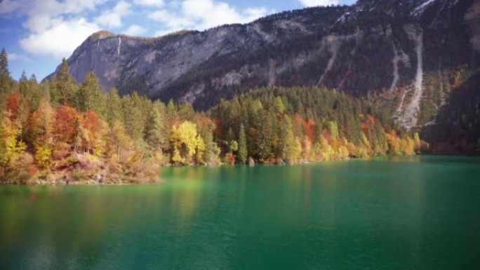 在阳光明媚的秋日，空中拍摄了风景秀丽的全景，在山上有树的湖上。