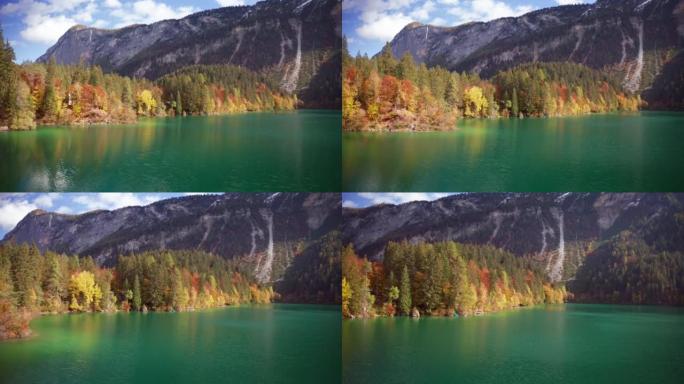 在阳光明媚的秋日，空中拍摄了风景秀丽的全景，在山上有树的湖上。