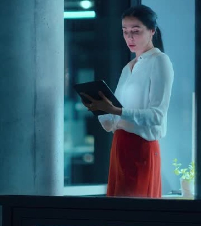外面的镜头: 女商人在办公室的平板电脑上工作。经理站在窗边检查电子邮件。垂直屏幕方向9:16的视频素
