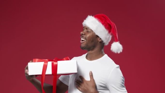 一个戴着圣诞帽的黑皮肤快乐男人转身从四面八方看着礼品盒