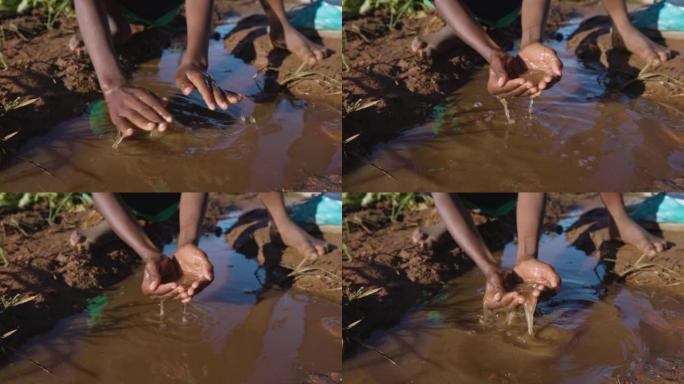 水危机。贫困。干旱。气候变化。全球变暖。不平等。年轻的非洲黑人用手舀脏水喝