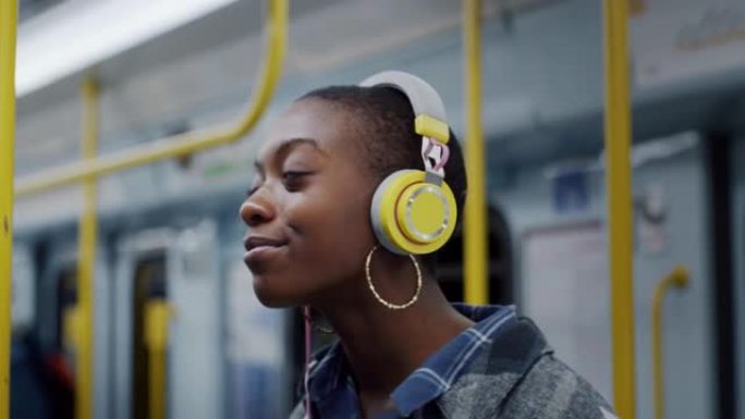 时尚的年轻黑人女性晚上在公共汽车上使用耳机和智能手机。得益于互联网平台，微笑和快乐的非洲裔美国人收听