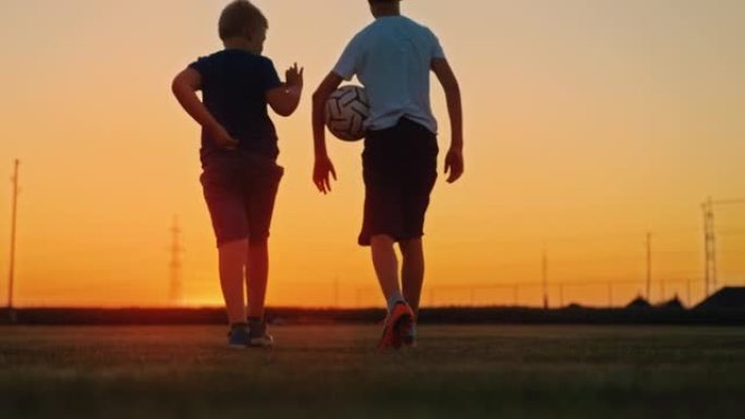 慢动作男孩与足球在黄昏时一起在田野里散步