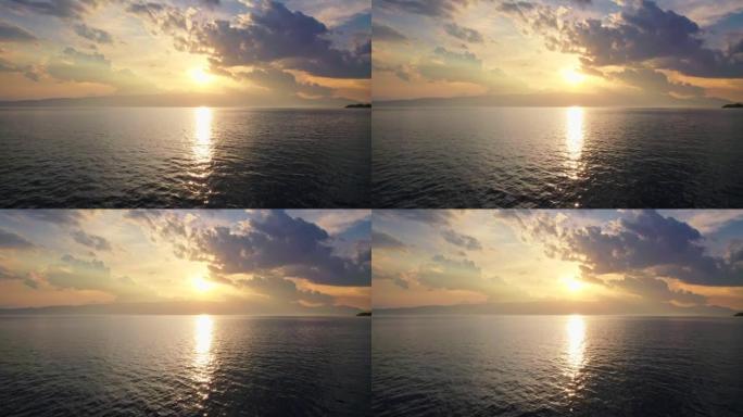 湖上的日落很大。相机在夕阳和五颜六色的云彩的背景下在水面上移动。湖泊和日落天空的鸟瞰图