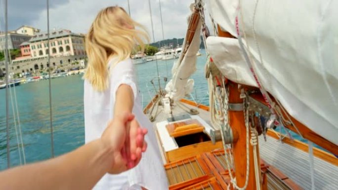 快乐的女人带领她的朋友牵着她的手走到船的前面。快乐的女人在游轮上，她的朋友走在意大利海洋上的船的前面