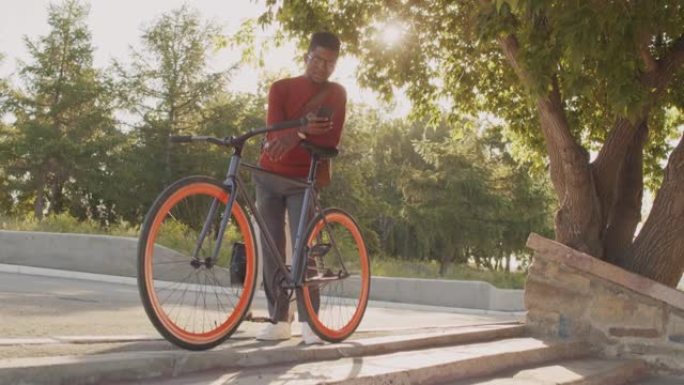 在户外使用智能手机骑自行车的非裔美国人