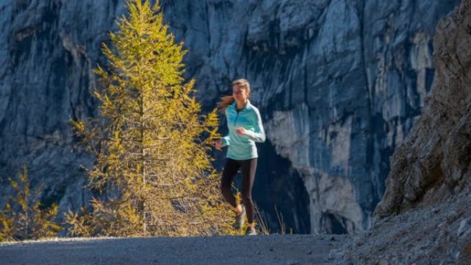 健康的女人保持健康的生活方式，在山里奔跑，周围风景迷人