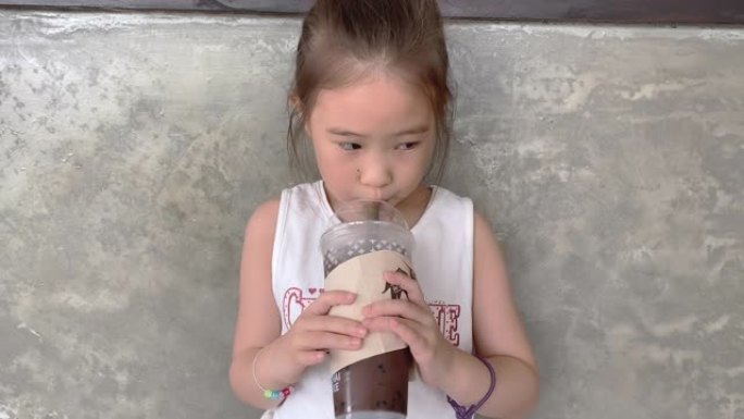 SLO MO可爱的小女孩在咖啡馆里喝冰巧克力