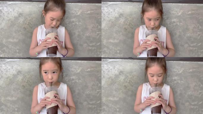 SLO MO可爱的小女孩在咖啡馆里喝冰巧克力